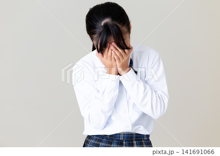 落ち込む制服姿の中学生の女の子・グレーバック 141691066