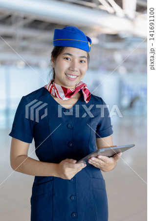 Airport ground service person, Asian beauty woman airline uniform standing happy smiling in airport Airport ground service person, Asian beauty woman airline uniform standing happy smiling in airport 141691100