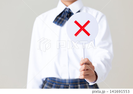 バツのプレートを持つ制服姿の中学生の女の子・グレーバック 141691553