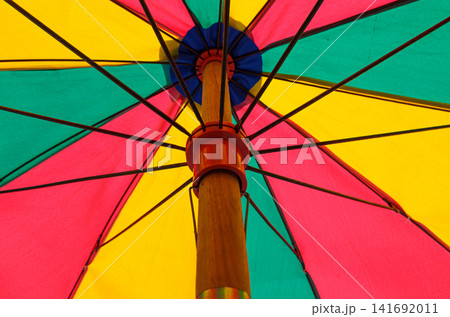 Low-angle view of a colorful beach umbrella canopy with vibrant geometric panels 141692011