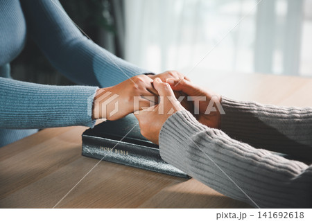 Close up of caring hands holding together over Holy Bible, showing Christian prayer support, pastoral care, compassion, healing and spiritual comfort. Close up of caring hands holding together over Holy Bible, showing Christian prayer support, pastoral care, compassion, healing and spiritual comfort. 141692618