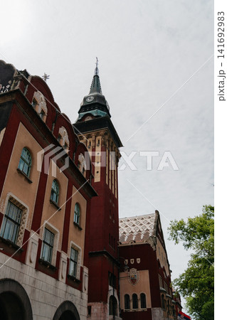 The clock tower and facade of Subotica City Hall rise above the street in Subotica, Serbia. Historic architecture, civic landmark, urban tourism, and European heritage The clock tower and facade of Subotica City Hall rise above the street in Subotica, Serbia. Historic architecture, civic landmark, urban tourism, and European heritage 141692983