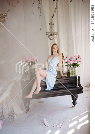 Woman sitting on piano amidst pink peonies and chandeliers Woman sitting on piano amidst pink peonies and chandeliers 141692992