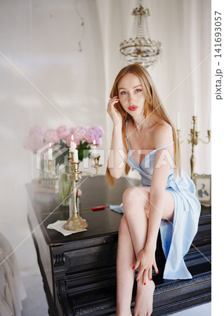 Redhead woman on grand piano by candlelight and flowers Redhead woman on grand piano by candlelight and flowers 141693057