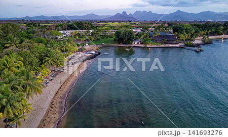Aerial high angle shot of a luxury beachfront resort, sandy cove, and private jetty at sunset in Mauritius 141693276