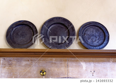 Antique pewter plates and ceramic earthenware jars on wooden dresser shelves at Dyrham Park Antique pewter plates and ceramic earthenware jars on wooden dresser shelves at Dyrham Park 141693332
