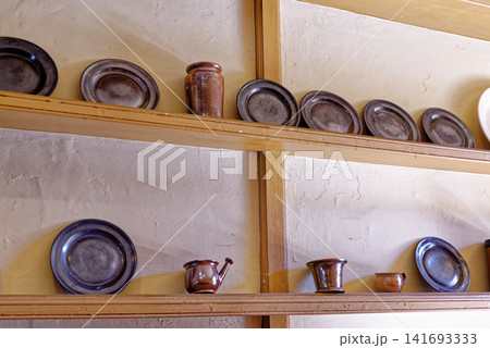Antique pewter plates and ceramic earthenware jars on wooden dresser shelves at Dyrham Park Antique pewter plates and ceramic earthenware jars on wooden dresser shelves at Dyrham Park 141693333