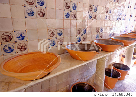 Traditional terracotta dairy bowls and marble table against Delft tiled walls in the dairy at Dyrham Park 141693340
