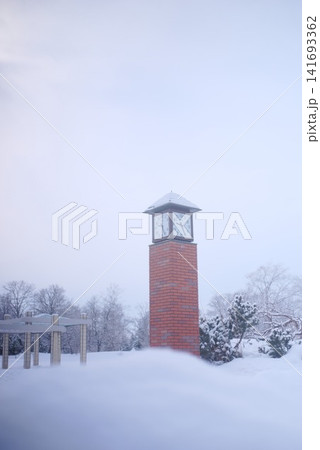 雪化粧した公園に佇むレンガ造りの時計塔と冬景色 雪化粧した公園に佇むレンガ造りの時計塔と冬景色 141693362
