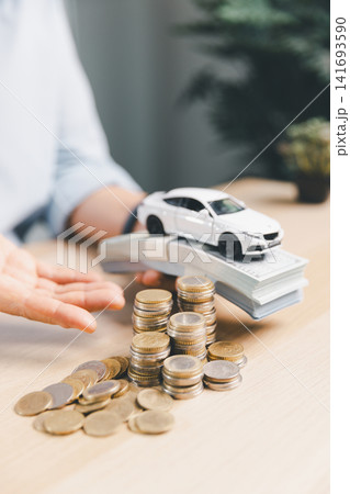 White toy car on cash bundle with coin stacks and hand presenting, representing car purchase payment, auto loan approval, down payment, and vehicle finance concept. White toy car on cash bundle with coin stacks and hand presenting, representing car purchase payment, auto loan approval, down payment, and vehicle finance concept. 141693590