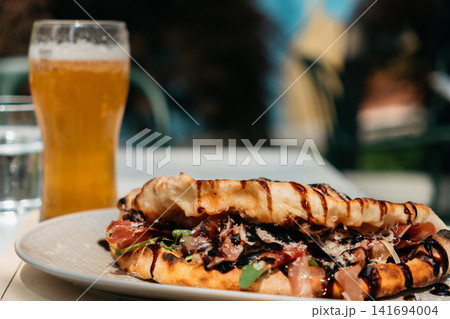 Crispy gourmet flatbread with prosciutto, greens and balsamic glaze served with cold draft beer. Premium pub meal creates a modern casual dining concept Crispy gourmet flatbread with prosciutto, greens and balsamic glaze served with cold draft beer. Premium pub meal creates a modern casual dining concept 141694004