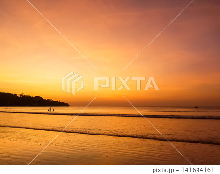 Sunset over Jimbaran Beach with silhouetted figures on shoreline, Bali, Indonesia Sunset over Jimbaran Beach with silhouetted figures on shoreline, Bali, Indonesia 141694161