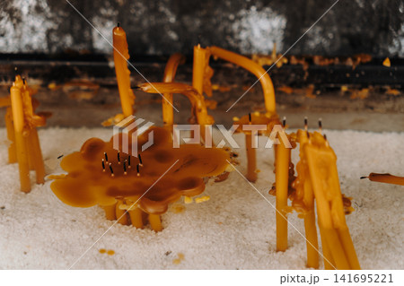 Melted wax and bent candles rest inside a prayer stand. Concept of spirituality, memory, faith and the passage of time 141695221