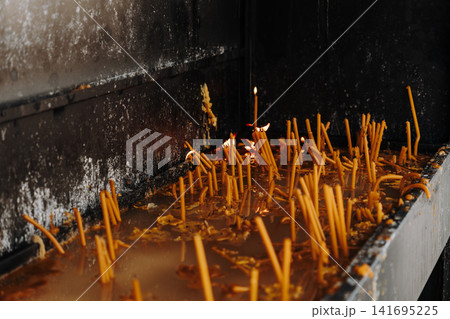 Burning candles glow inside a blackened religious shrine. Concept of faith, remembrance, spirituality and peaceful reflection 141695225