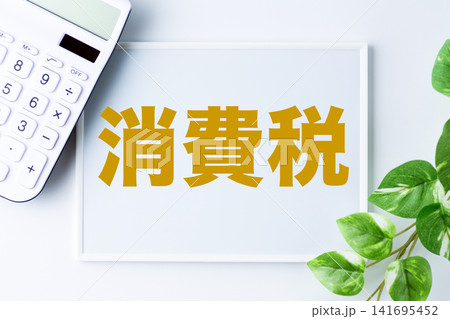 消費税の文字のホワイトボードと白い電卓 消費税の文字のホワイトボードと白い電卓 141695452