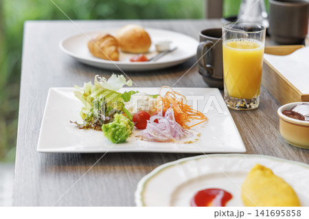 テーブルに配置されたサラダとオムレツとジュースの朝食セット 141695858