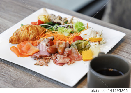 クロワッサンや生ハムなどが豪華に盛られた朝食プレートとコーヒー 141695863