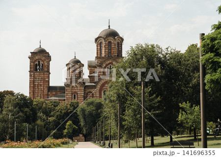Saint Mark's Church rises above the trees in Tasmajdan Park in Belgrade, Serbia. Historic Orthodox architecture surrounded by lush greenery in a peaceful urban setting Saint Mark's Church rises above the trees in Tasmajdan Park in Belgrade, Serbia. Historic Orthodox architecture surrounded by lush greenery in a peaceful urban setting 141696355