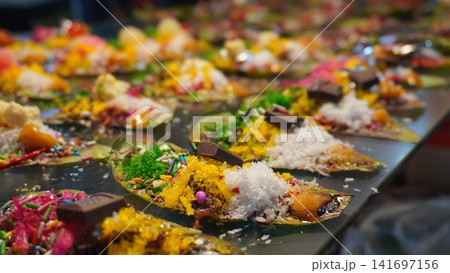 Colorful paan topped with sweets and coconut in vibrant festive arrangement, traditional dessert concept Colorful paan topped with sweets and coconut in vibrant festive arrangement, traditional dessert concept 141697156