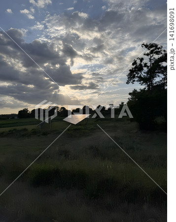 Sunset over a field with solar panels in the distance 141698091