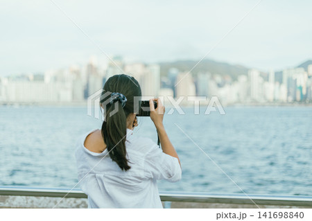 a young woman take pictures of a city view. 141698840