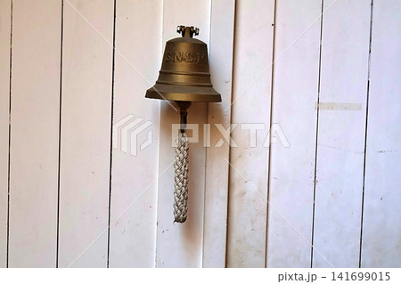Vintage Brass Ship's Bell with Rope on White Wooden Wall. Vintage Brass Ship's Bell with Rope on White Wooden Wall. 141699015