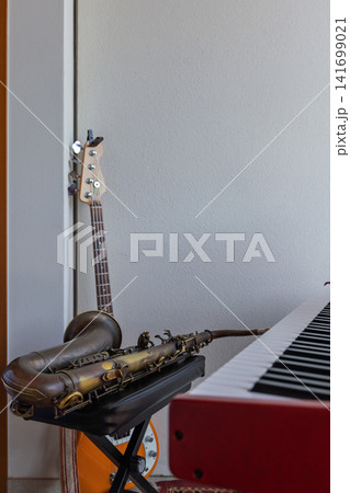 Tenor saxophone, bass guitar and electronic keyboard in a home music setup 141699021