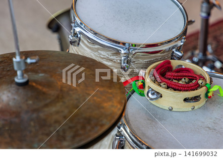 Tambourine resting on a drum head beside a cymbal in a percussion setup Tambourine resting on a drum head beside a cymbal in a percussion setup 141699032