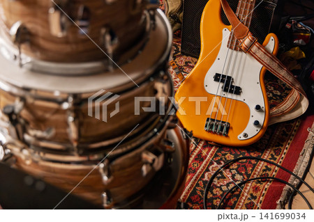 Four-string electric bass beside wood-grain drums in warm vintage tones 141699034