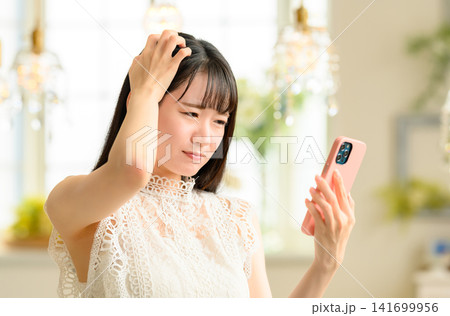 スマホを操作し悩む女性 スマホを操作し悩む女性 141699956