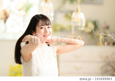 笑顔で髪を触る白い服の女性 笑顔で髪を触る白い服の女性 141699963
