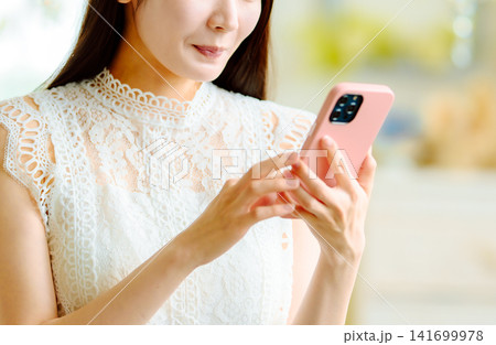 ピンクのスマホを持つ女性の手元 141699978