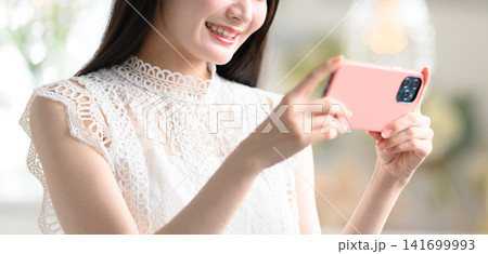 スマホを横向きに持つ女性 141699993