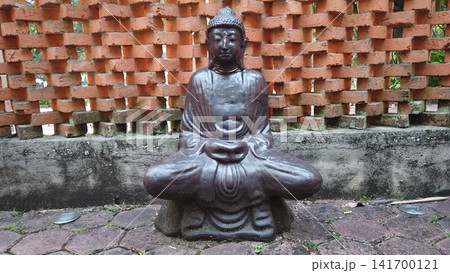 Serene Meditating Buddha Statue Against Textured Brick Wall 141700121