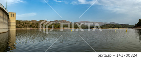 View of Beniarres reservoir showing water surface, dam, buoys, and mountains in background during daylight View of Beniarres reservoir showing water surface, dam, buoys, and mountains in background during daylight 141700824