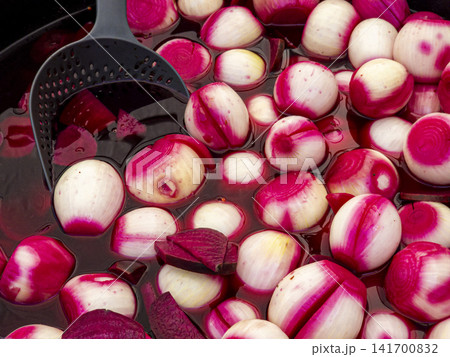 Small white onions and sliced red beets pickling in a large dark vat for food preparation Small white onions and sliced red beets pickling in a large dark vat for food preparation 141700832