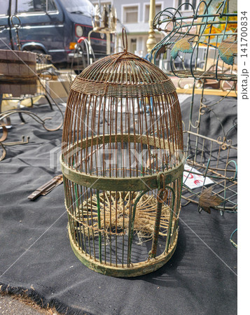 Xalo, Spain - June 20, 2026.Vintage rusted wire birdcage for sale at outdoor flea market among various antiques and items 141700834