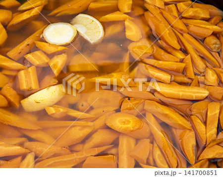 Chopped fresh carrots and citrus slices soaking in liquid at a food market 141700851