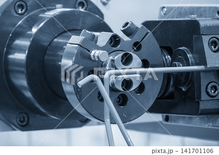 Automatic wire coil spring bending machine operation in blue tone lighting. Automatic wire coil spring bending machine operation in blue tone lighting. 141701106
