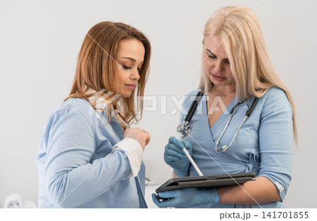 Medical teamwork is demonstrated as two women review data on a tablet, emphasizing digital solutions in clinical practice. The setting is bright and professional, reflecting modern healthcare trends Medical teamwork is demonstrated as two women review data on a tablet, emphasizing digital solutions in clinical practice. The setting is bright and professional, reflecting modern healthcare trends 141701855