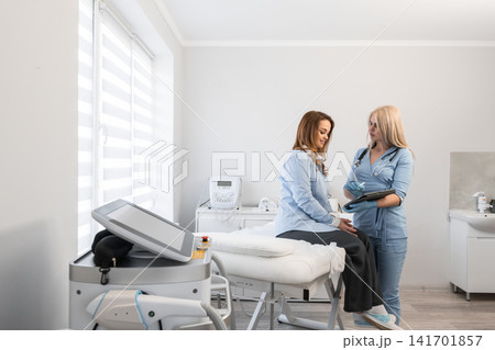A healthcare professional measures blood pressure of a female patient in a contemporary medical office. The scene highlights trust, modern technology, and a supportive doctor patient relationship A healthcare professional measures blood pressure of a female patient in a contemporary medical office. The scene highlights trust, modern technology, and a supportive doctor patient relationship 141701857