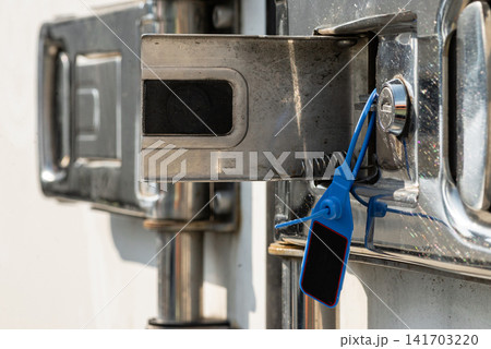 Detailed view of a blue security tag locking a truck cargo door 141703220