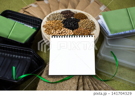 Top view shows microgreens tray with sprouts and white empty place as mockup. Natural materials surround composition with white blank paper for text as mockup. Top view shows microgreens tray with sprouts and white empty place as mockup. Natural materials surround composition with white blank paper for text as mockup. 141704329