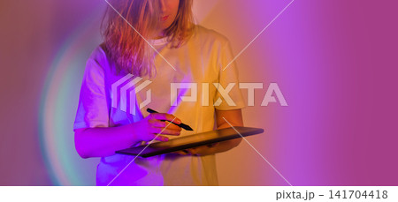 Girl digital artist with a transparent tablet ultra modern. Art media and entertainment in virtual digital metaverse. Girl digital artist with a transparent tablet ultra modern. Art media and entertainment in virtual digital metaverse. 141704418