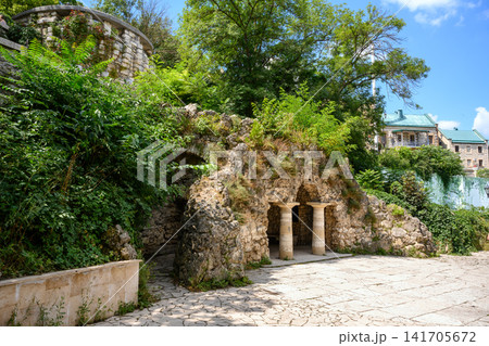 Stone grotto of Diana with classical columns in a lush green park in Pyatigorsk, Russia. Artificial cave structure overgrown in a landscaped garden. Historical architecture on a sunny summer day 141705672