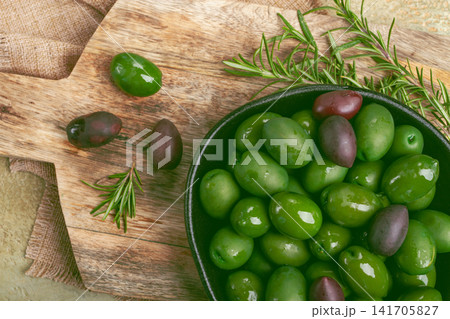 Chalkidiki olives, classic Greek green olives, in a bowl on a cutting board, top view, without people, Chalkidiki olives, classic Greek green olives, in a bowl on a cutting board, top view, without people, 141705827