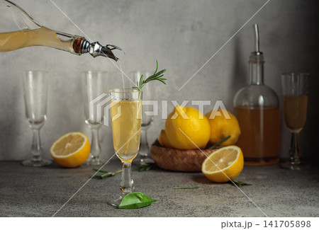 Italian liqueur Limoncello with fresh lemons and rosemary branches on a gray stone table. Italian liqueur Limoncello with fresh lemons and rosemary branches on a gray stone table. 141705898