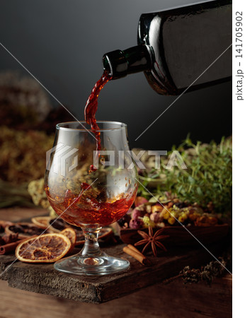 Herbal bitter liqueur is poured from a vintage bottle into a glass. Herbal bitter liqueur is poured from a vintage bottle into a glass. 141705902