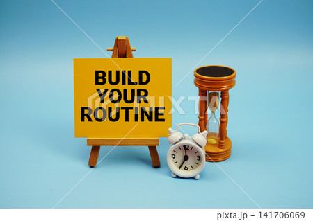 Build Your Routine text with alarm clock and hourglass on blue background Build Your Routine text with alarm clock and hourglass on blue background 141706069