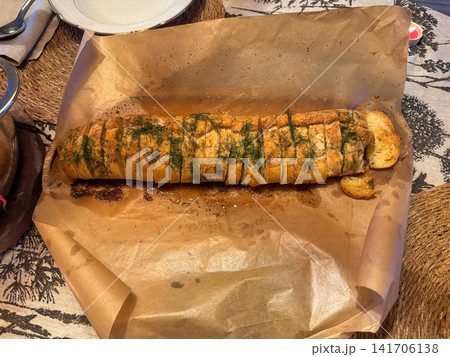 Sliced garlic baguette with fresh dill baked on parchment paper 141706138